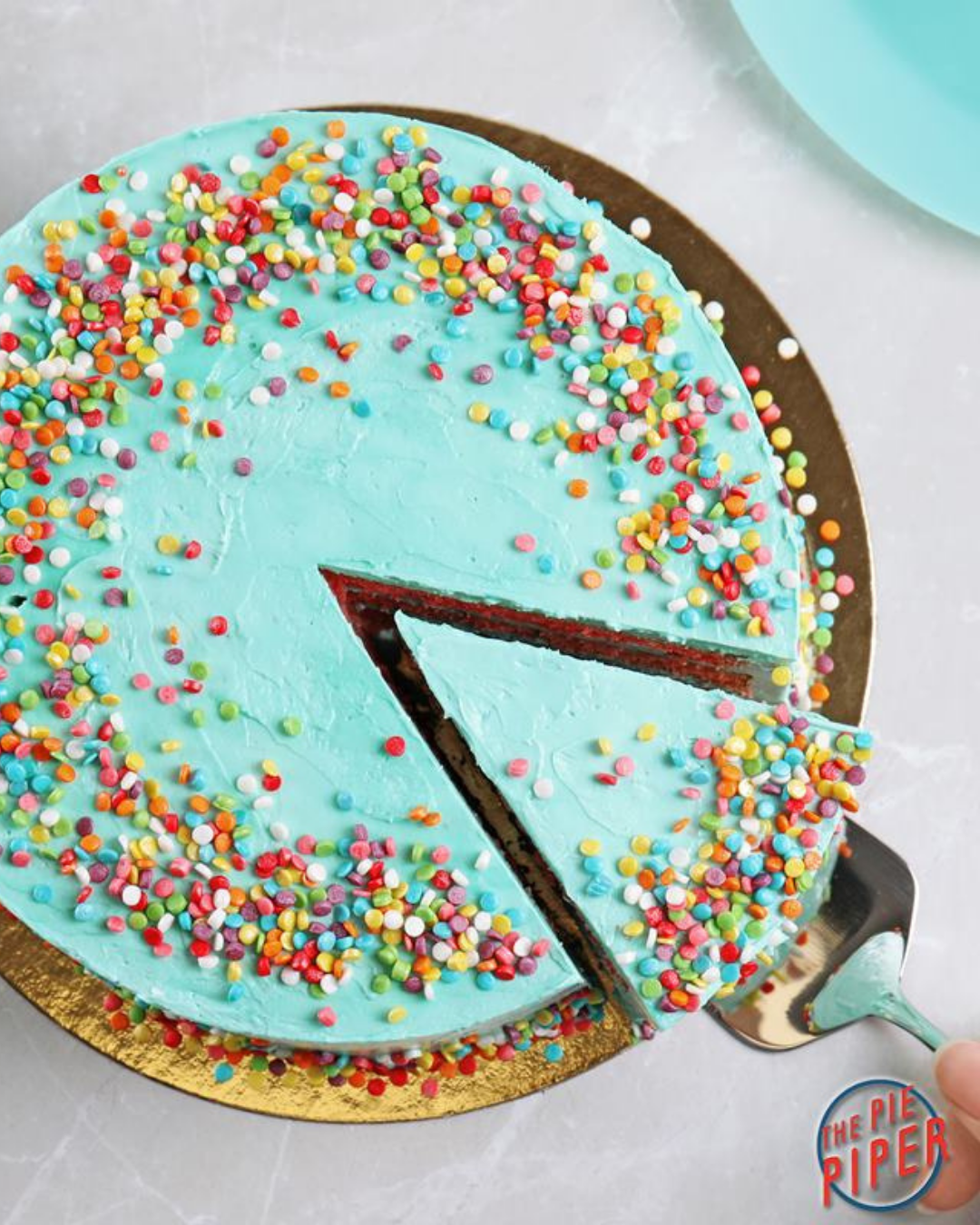 Birds eye view of a vibrant light blue cake with chunky multicoloured sprinkles. 