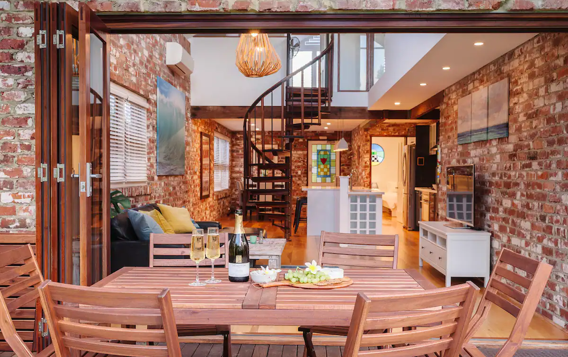 from the decking area we look into a warm and inviting open plan living room with exposed brick and jarrah timber