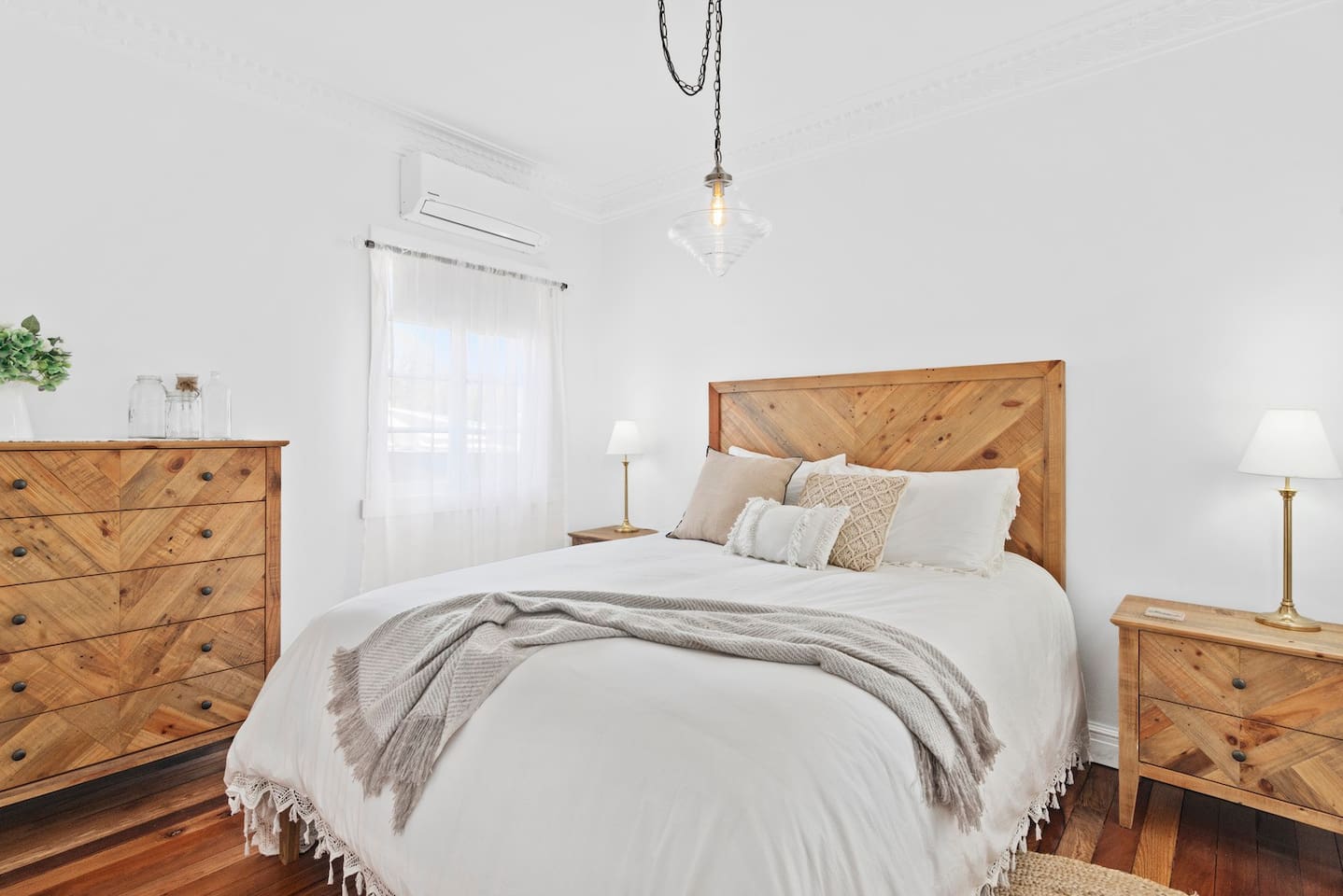 a stylish white bedroom with a beautifully made bed