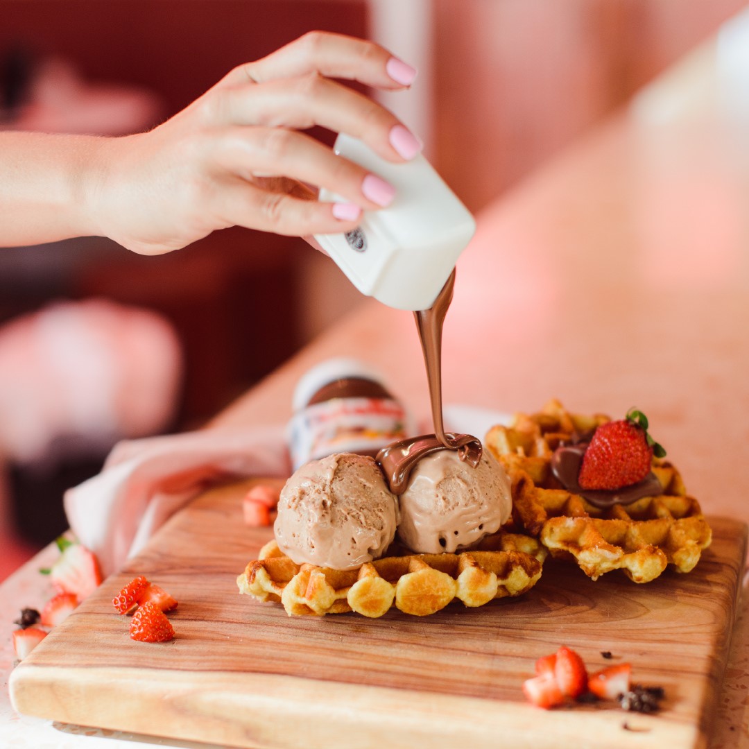 a waffle with ice cream and nutella being poured over top