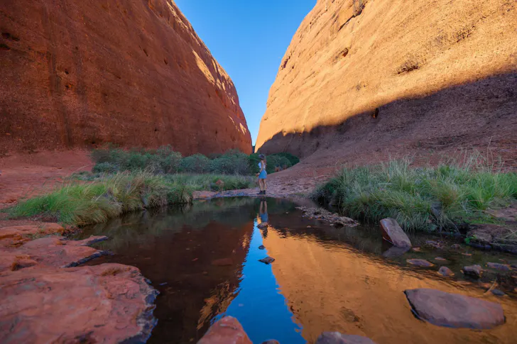 A person stands between the towering red boulders of Walpa Gorge, Kata Tjuta
