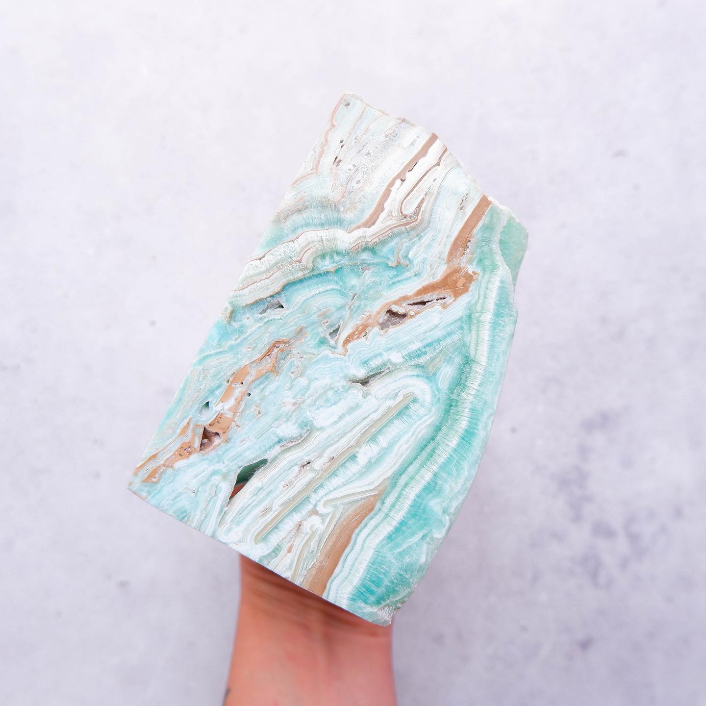 a hand holding slab of aqua crystal