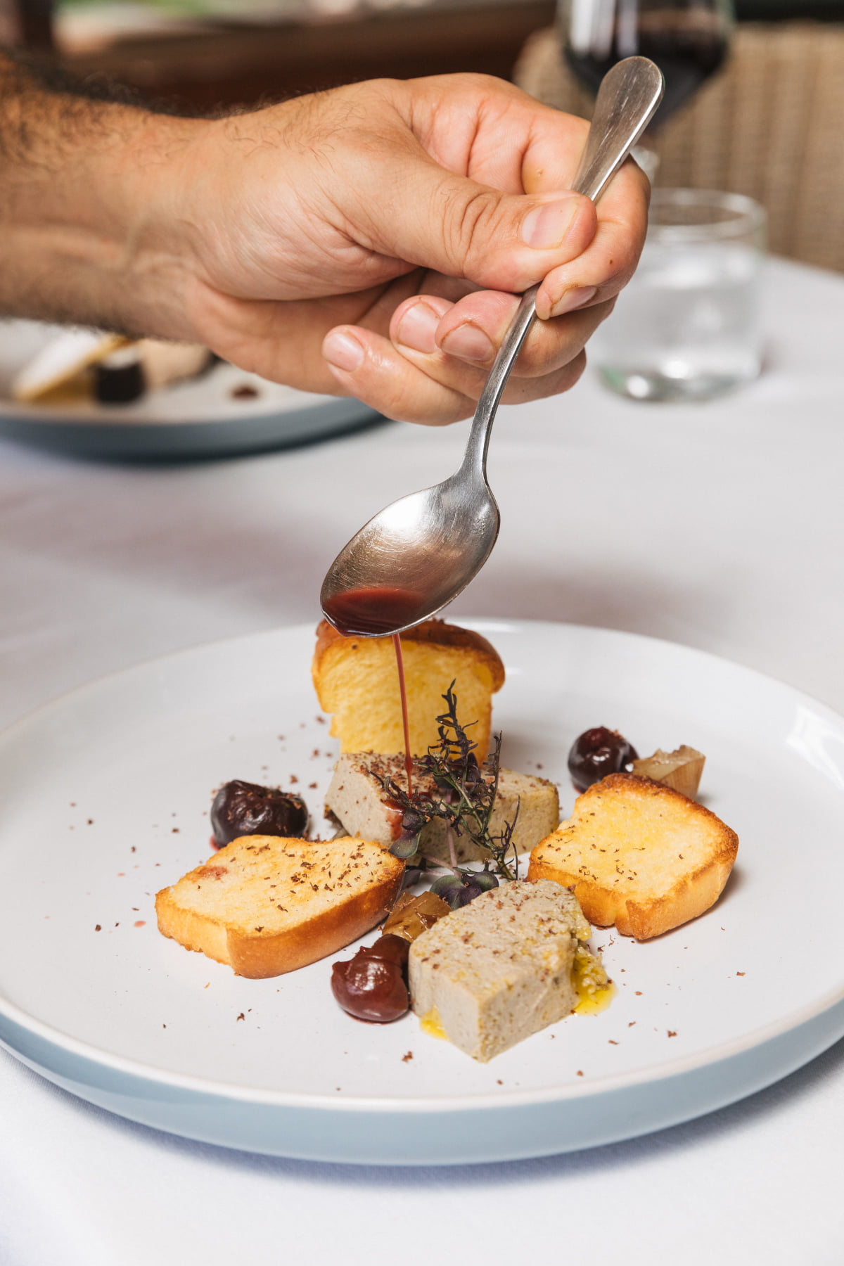 Sauce being poured over a well plated dish 