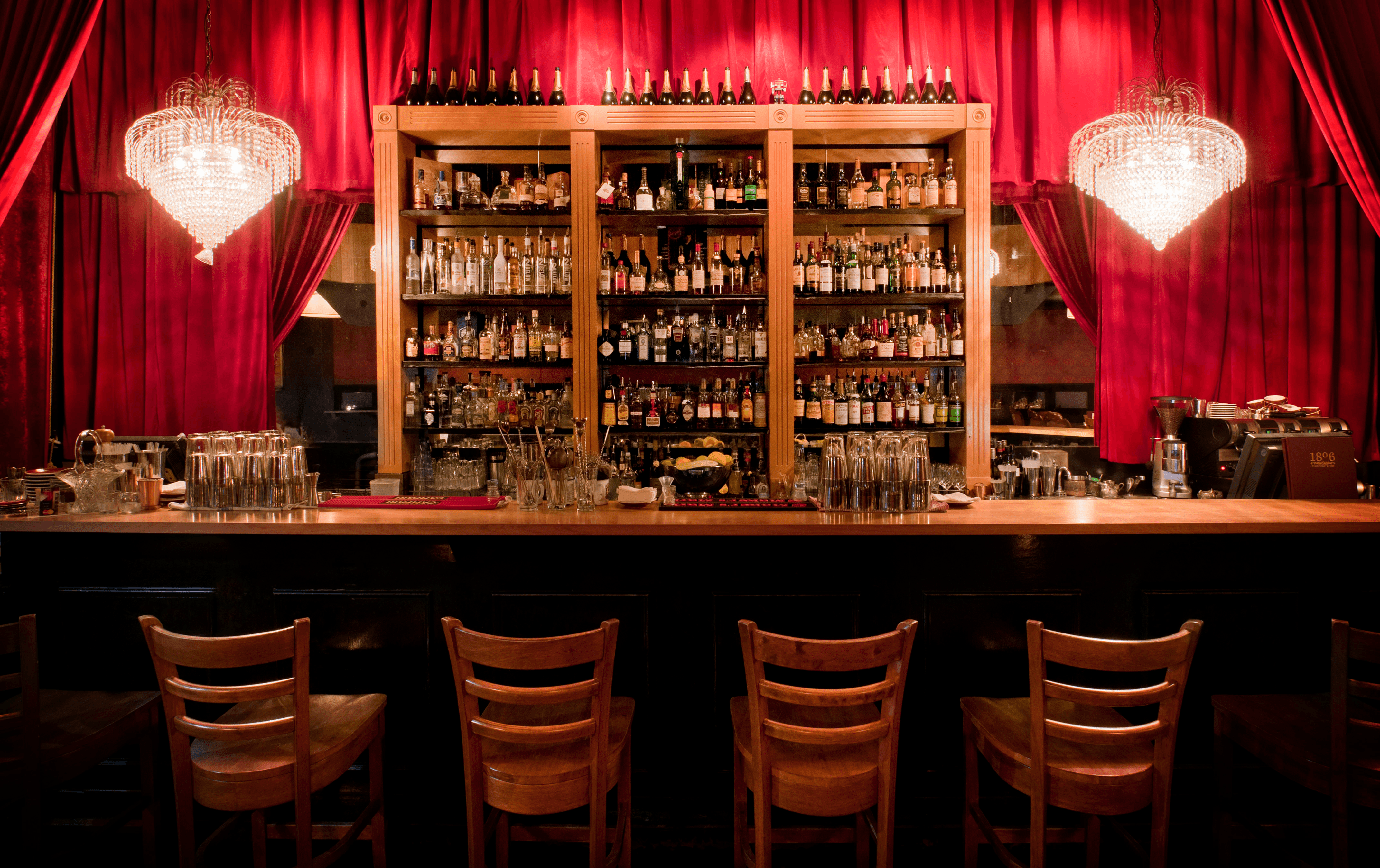 A red curtain bar, a shelves lined with bottles a top cocktail bar Melbourne. 
