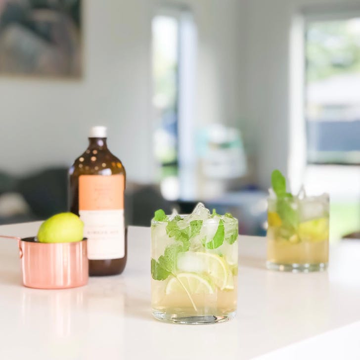 two mojitos in front of a bottle of syrup