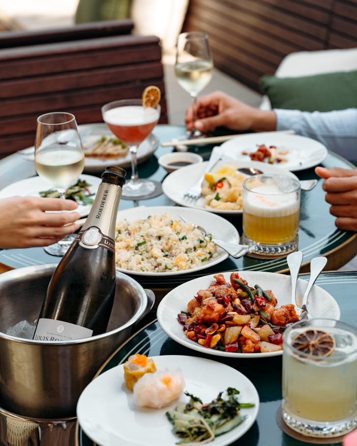 a table filled with chinese food and cocktails