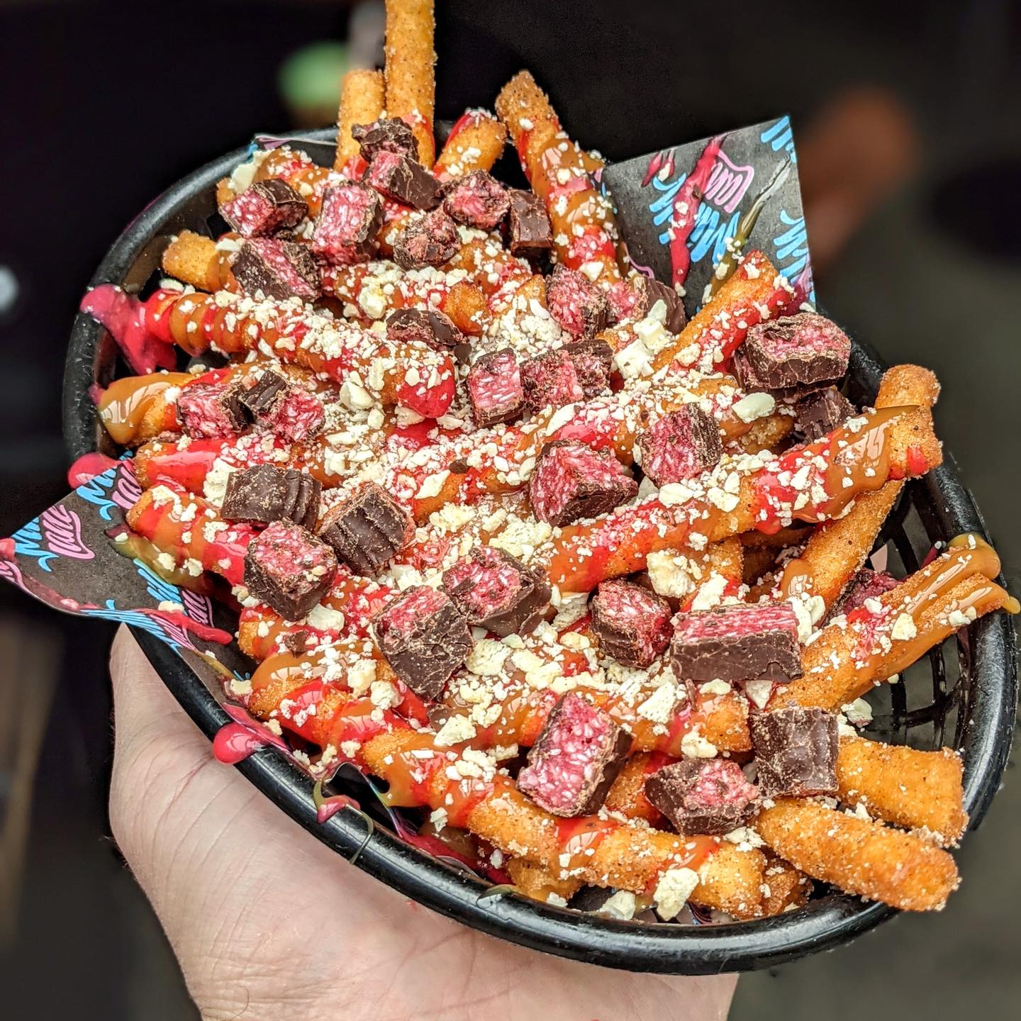 a basket of doughnut fries topped with chunks of cherry ripe