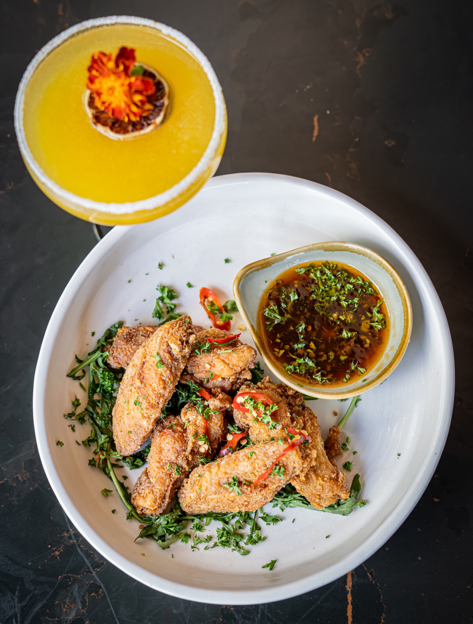 a plate of crispy wings with a cocktail