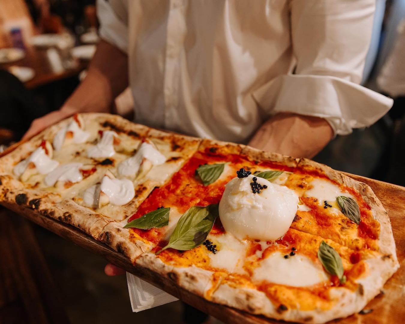 A large pizza topped with a ball of burrata cheese.