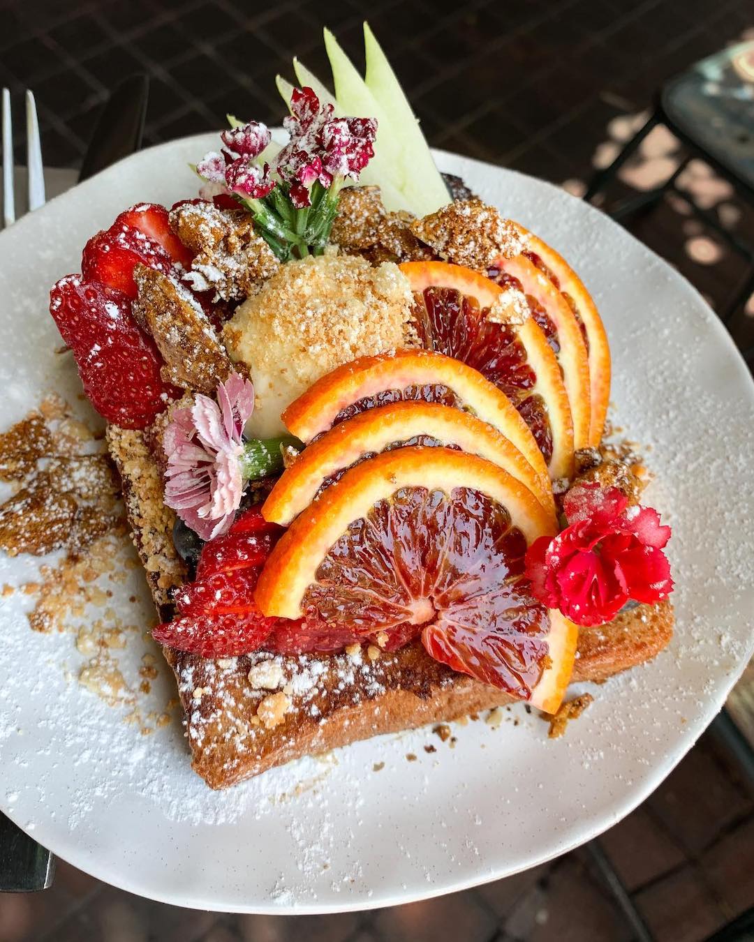 An elaborate French toast covered with citrus and flowers.