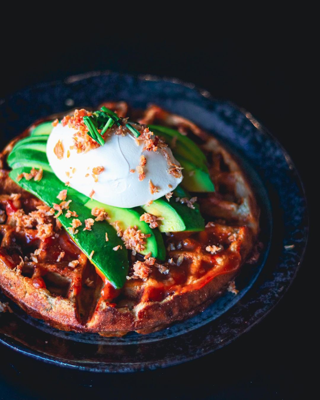 a waffle with eggs and avocado