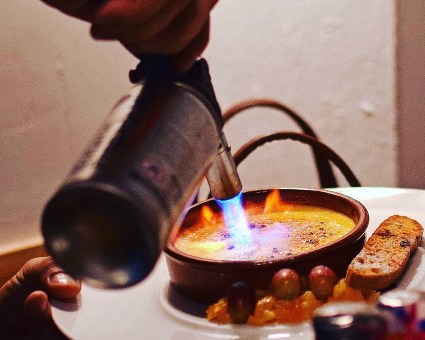 A culinary torch crisping the top of a creme brulée 