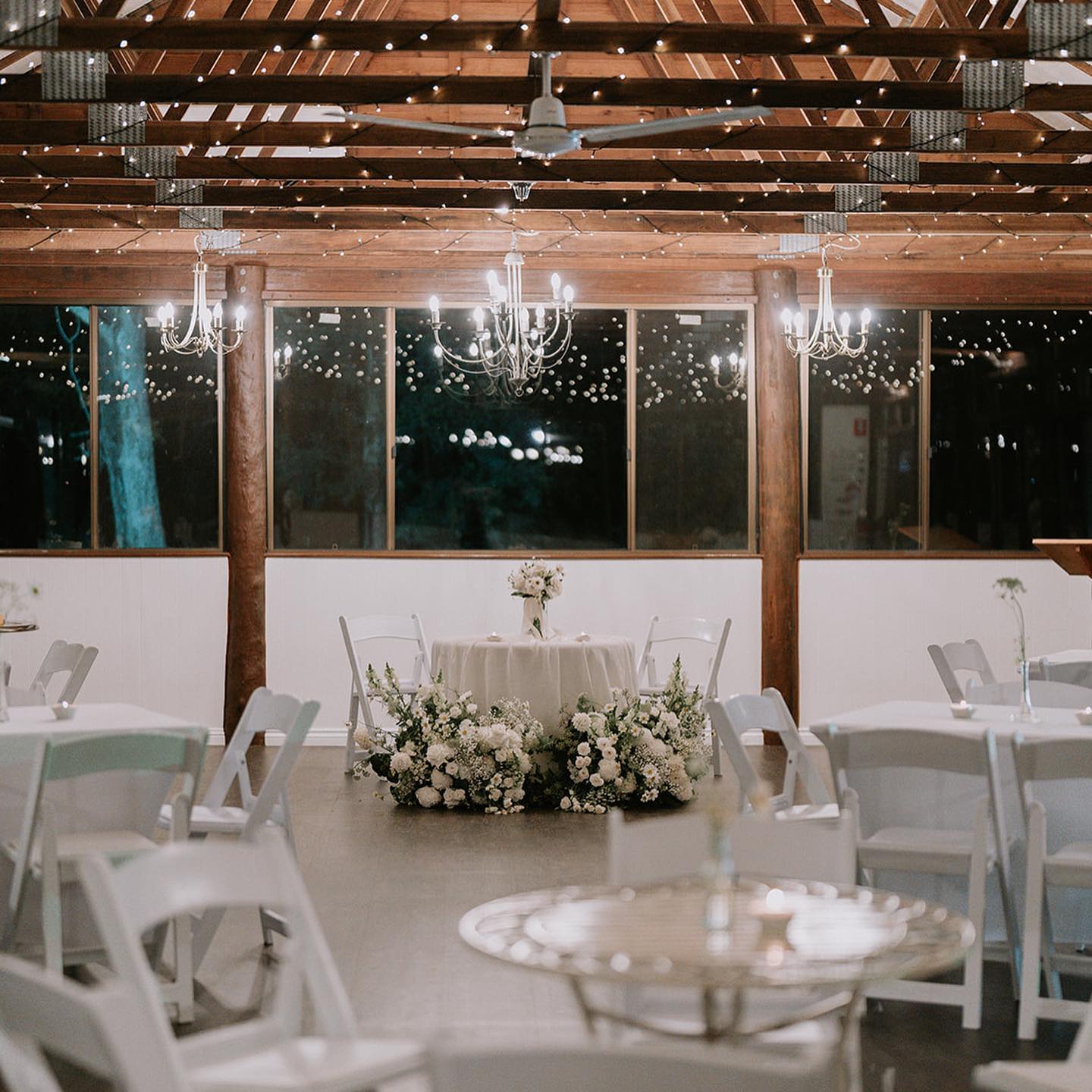 a barn like room filled with white tables at a a wedding venue near brisbane