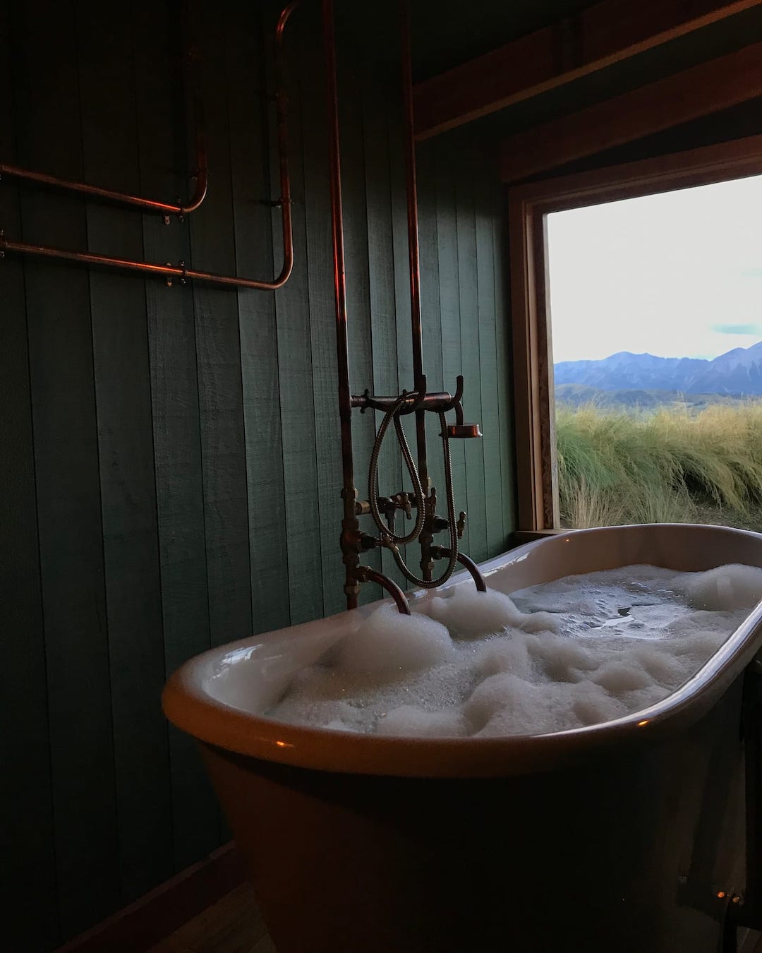 A moody bath looks out onto green fields.