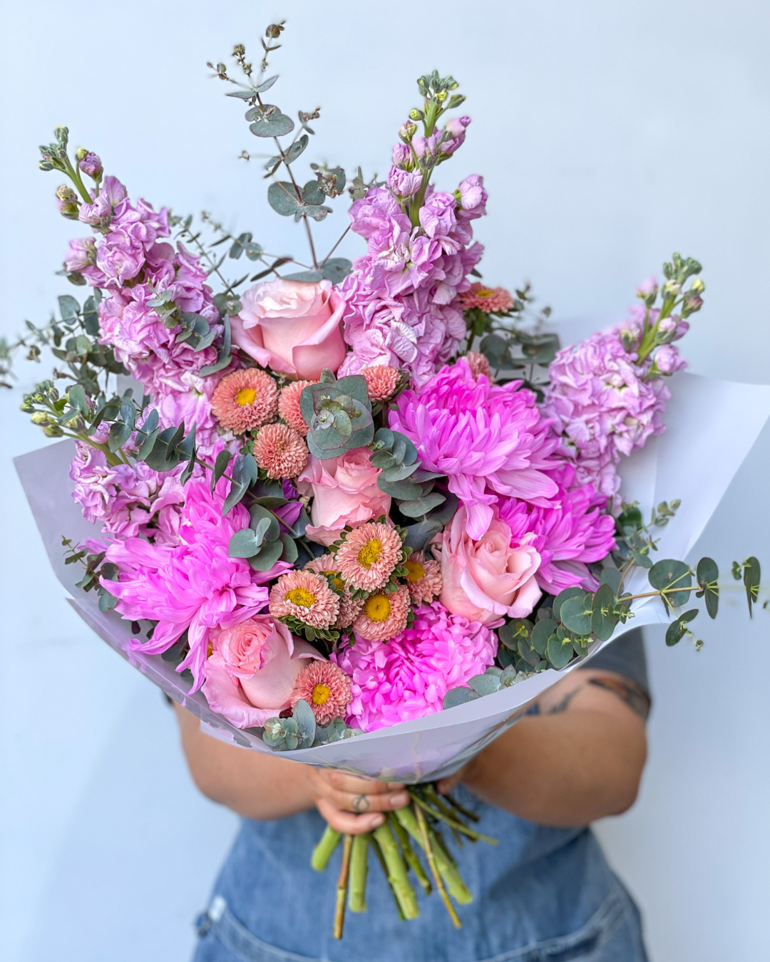 a person behind a huge bouquet of pink flowers