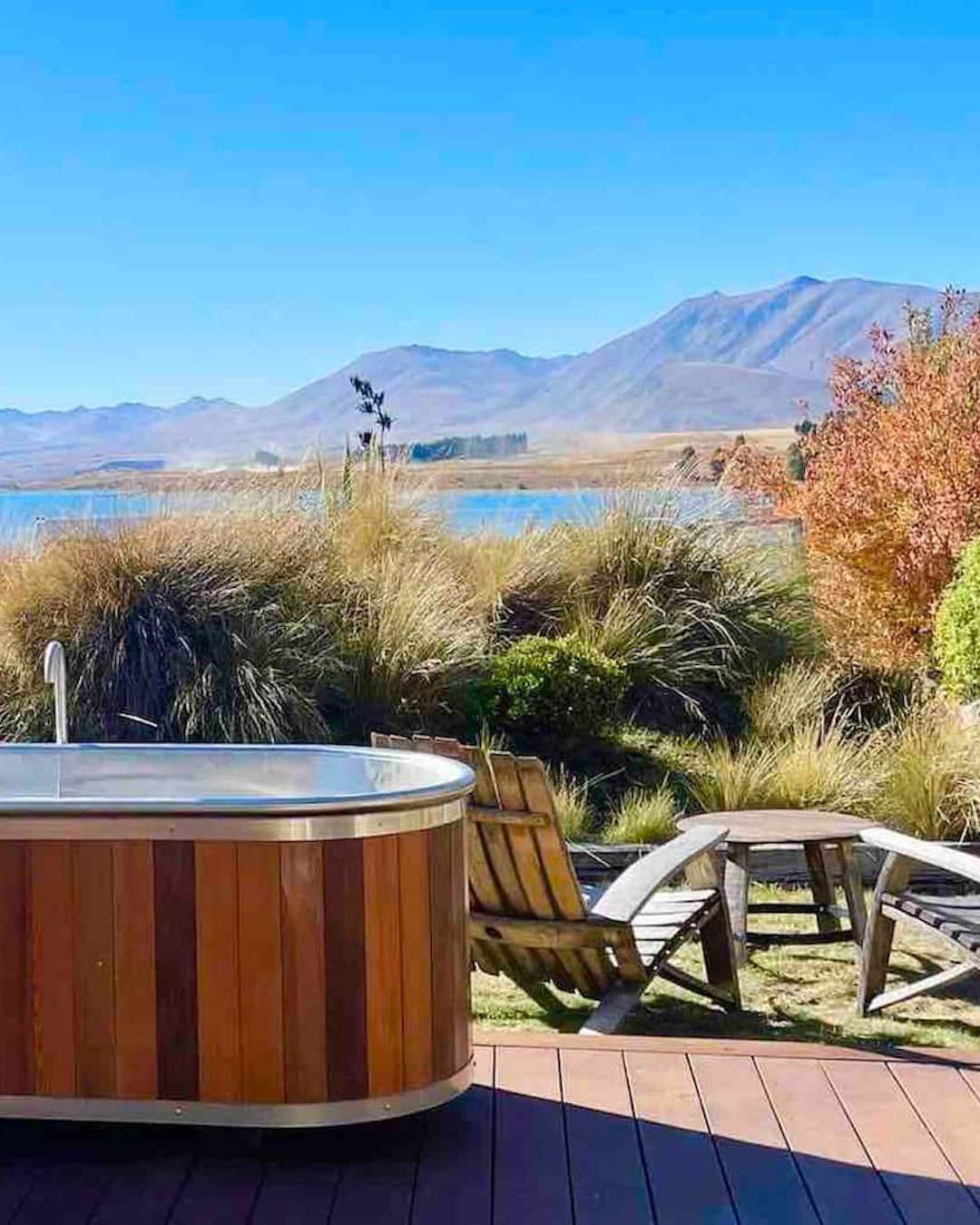 A hot tub and garden setting with views of mountains and a lake