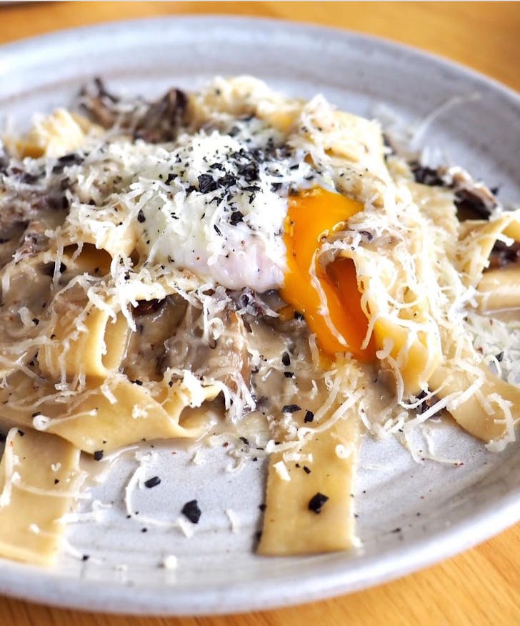 a plate of pappardelle topped with egg