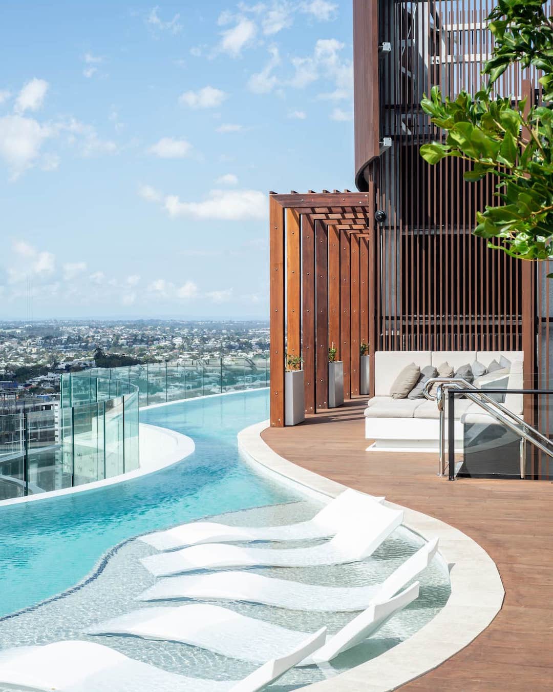 A sparkling rooftop pool with sun lounges under a clear sky.