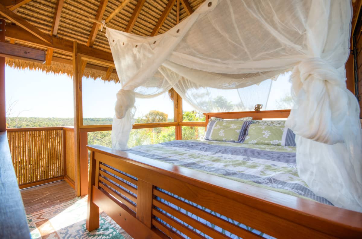 a double bed with a canopy in a treehouse