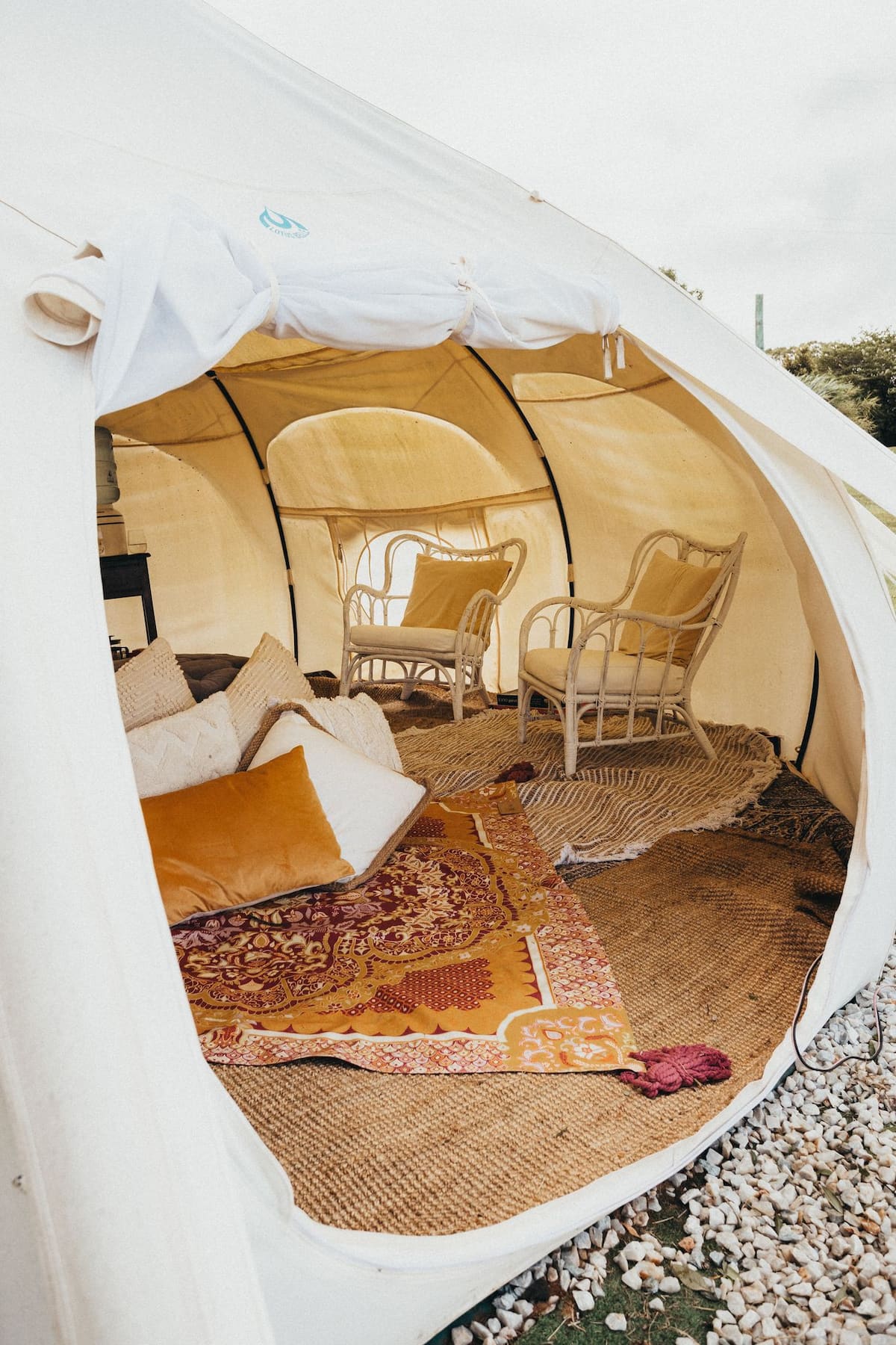 interior of a tent with wicker chairs and a cosy bed