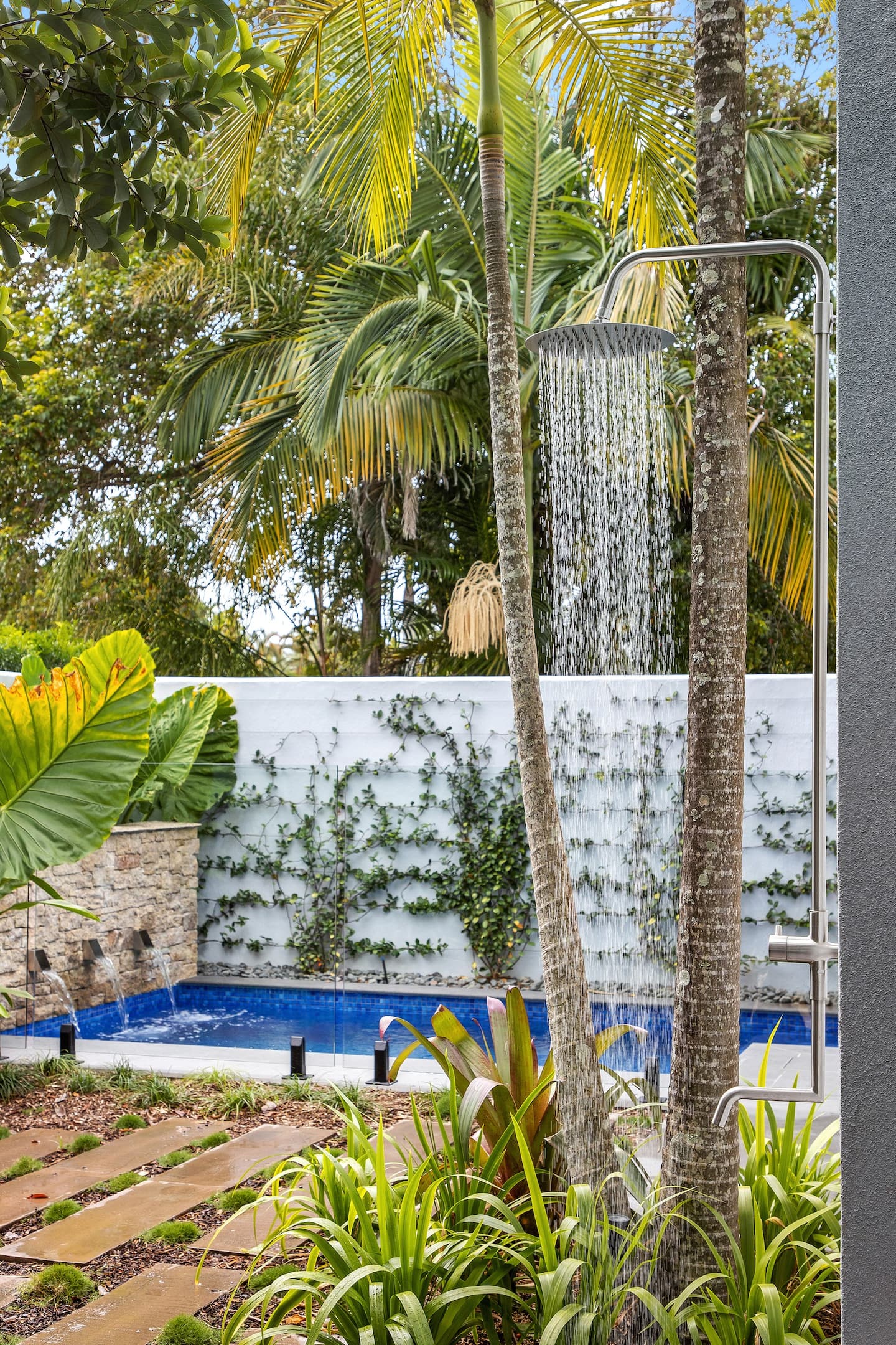 an outdoor shower with a pool in the background