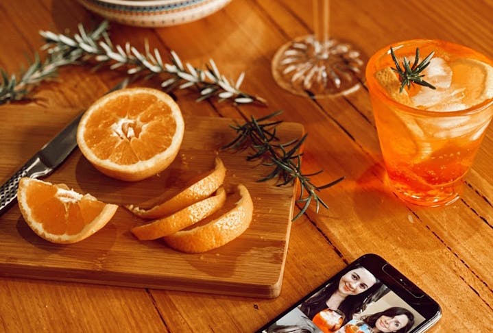 An Aperol Spritz sits next to orange slices and a phone. 