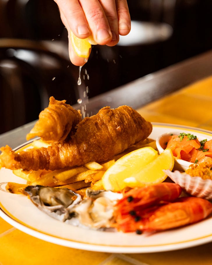A close up image of a hand squeezing lemon on a seafood platter.