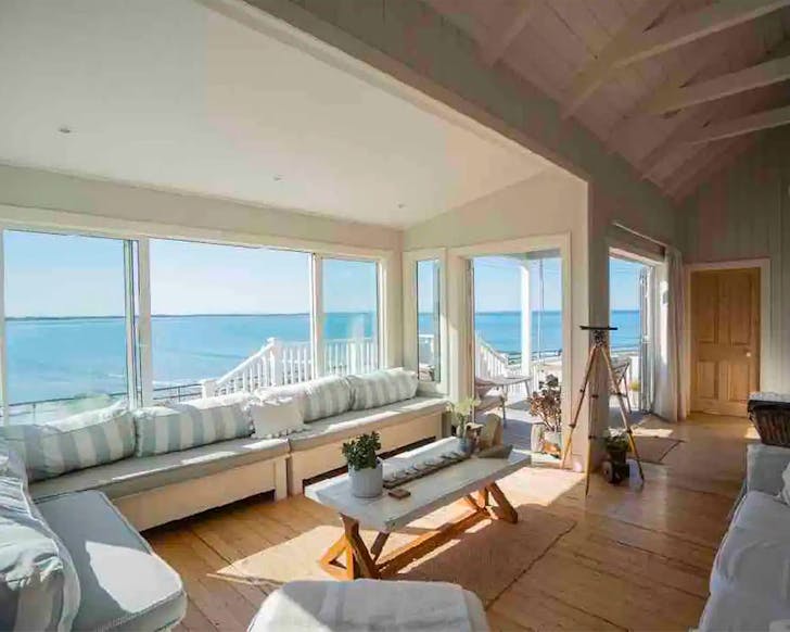 A lovely view out of the window from an expansive living room with wooden floors.
