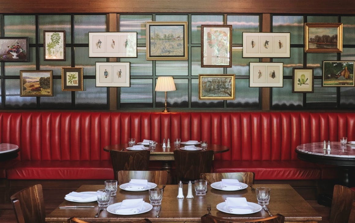 Red booth seating, with photos on back wall of restaurant. 