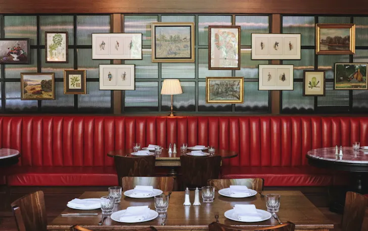 Red booth seating, with photos on back wall of restaurant. 
