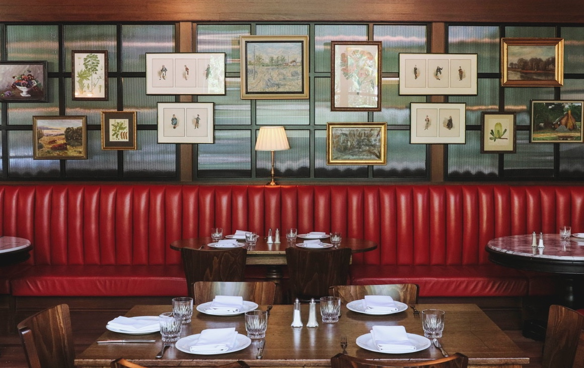 Red booth seating, with photos on back wall of restaurant. 