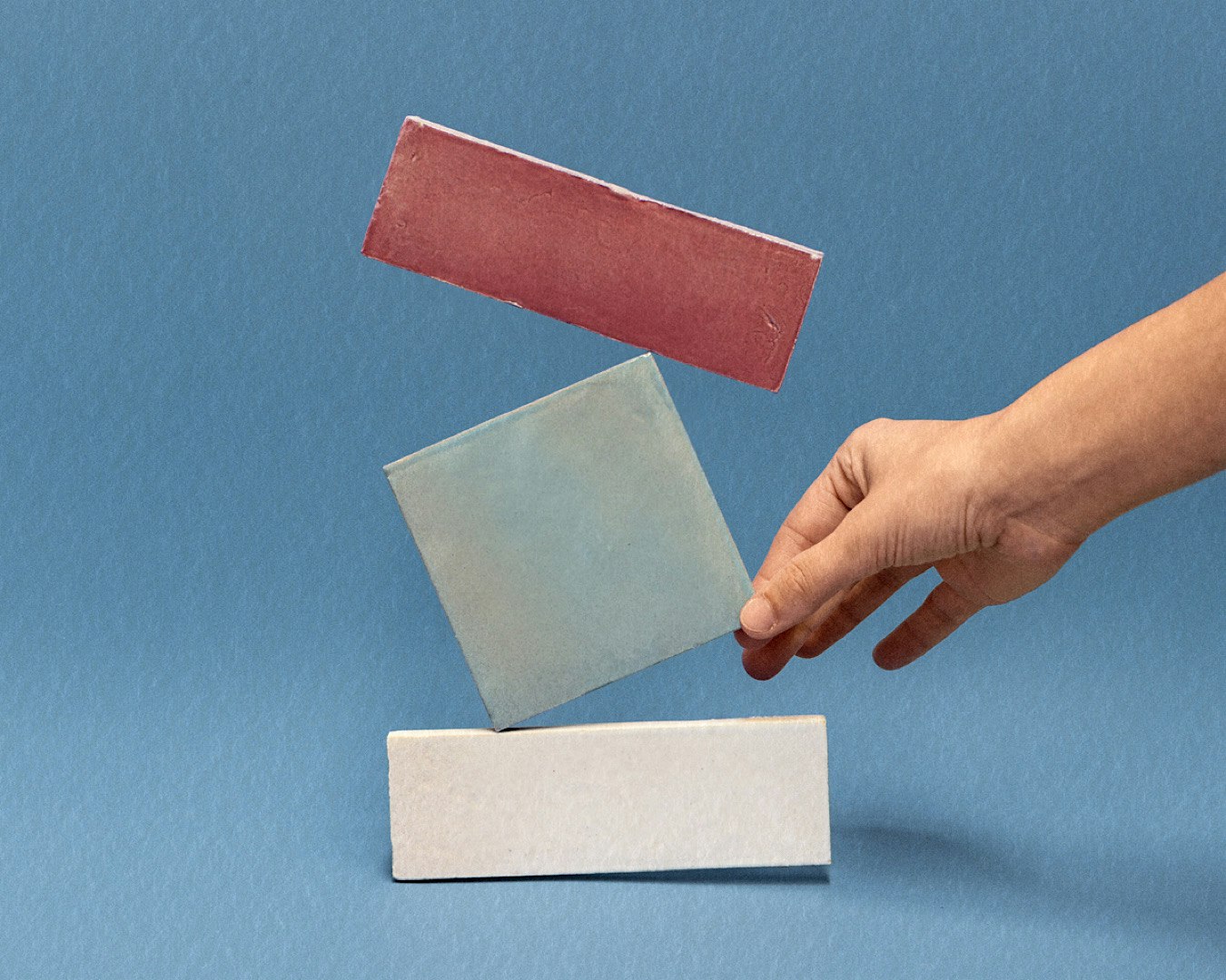 Somebody holds a blue square tile.