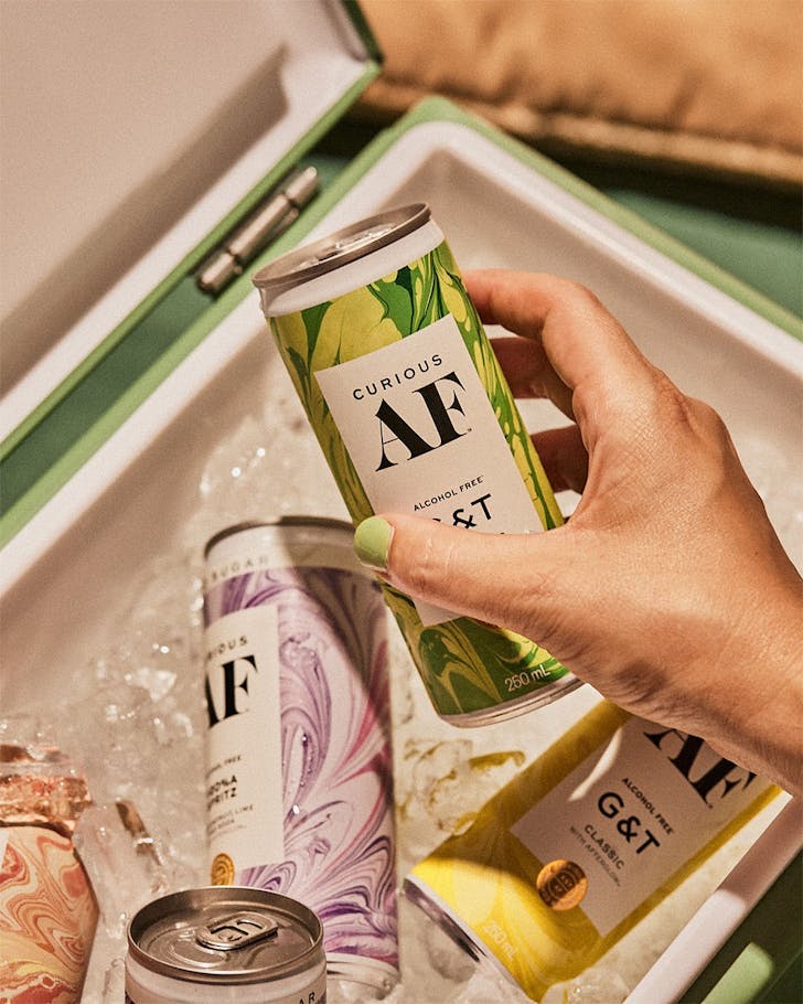 Someone reaches for an AF Drinks G&T from a cooler.