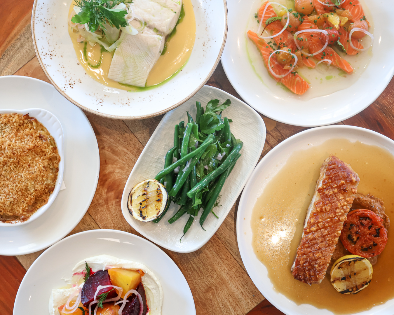 Above view of many seafood dishes nicely displayed on restaurant plates, including salmon, vegetables, and steamed fish. at one of the best restaurants in sydney for fathers day 2025 deckhouse