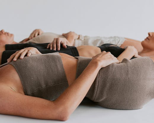 three women laying on the floor in a yoga studio