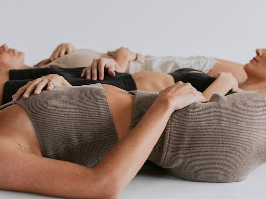 three women laying on the floor in a yoga studio