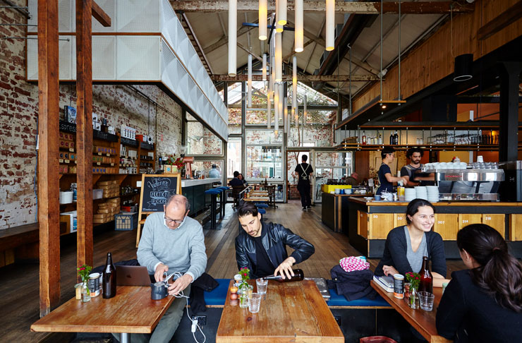 a large industrious warehouse with people drinking coffee at one of the best cafes Melbourne has in 2023.