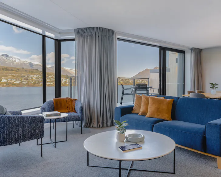 A minimalistic, apartment-style room with floor-to-ceiling lake and mountain views.