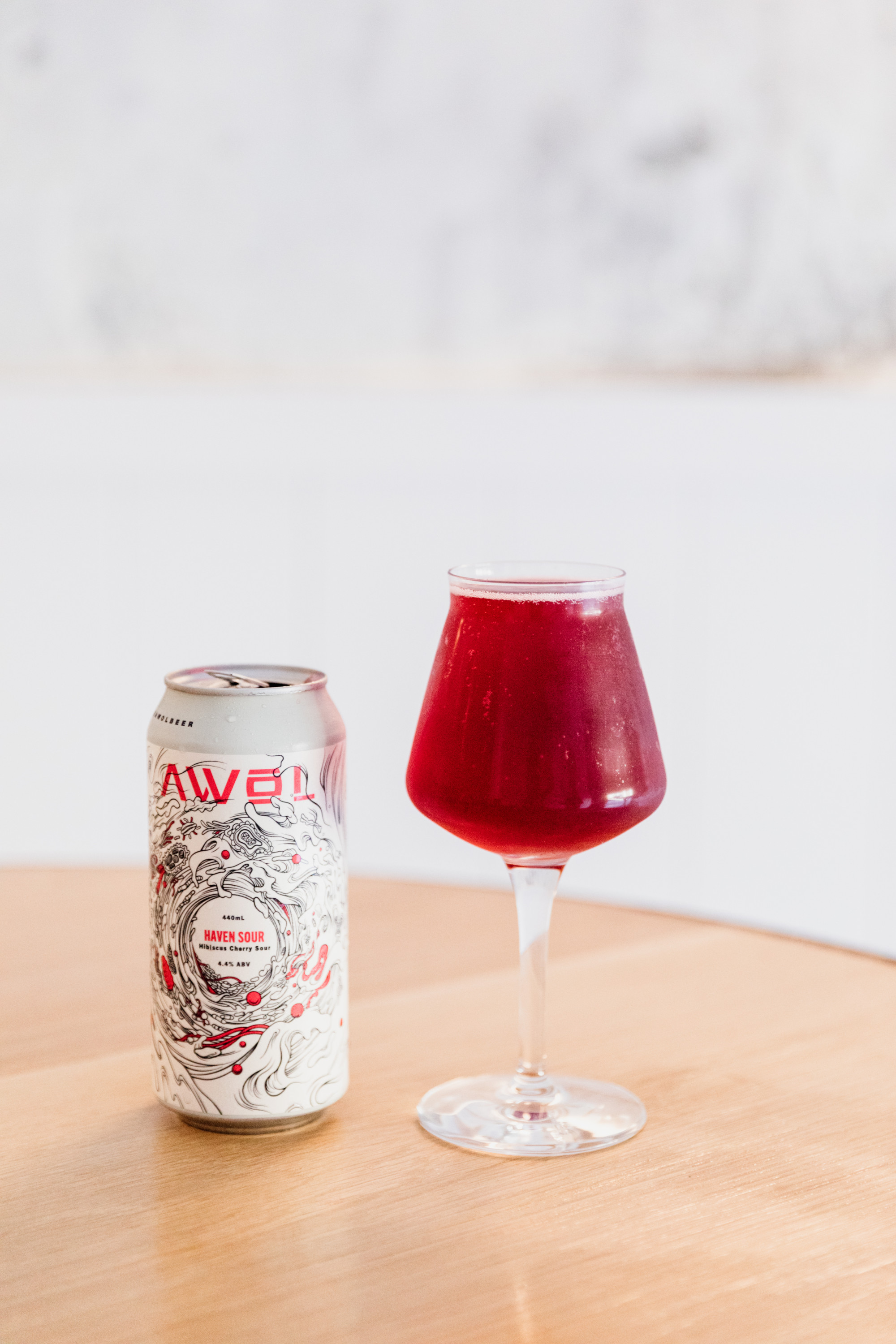 a red sour beer in a glass next to a can