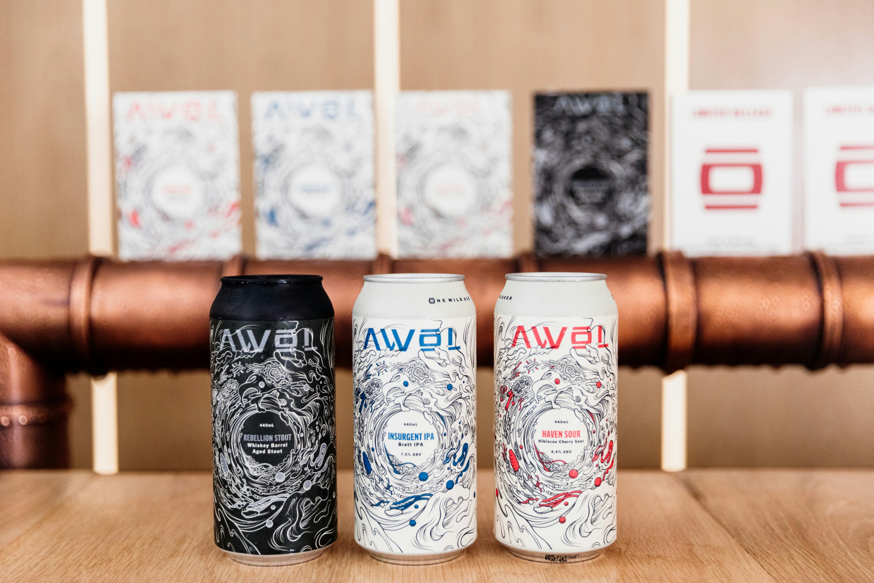 three cans of beer against a row of beer taps