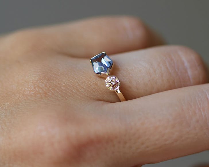 A brilliant angular blue stone next to a round blush stone on a thin ring band by Figursky  