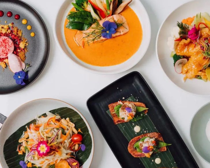 A table with various colourful dishes including snapper, tofu strips and salad