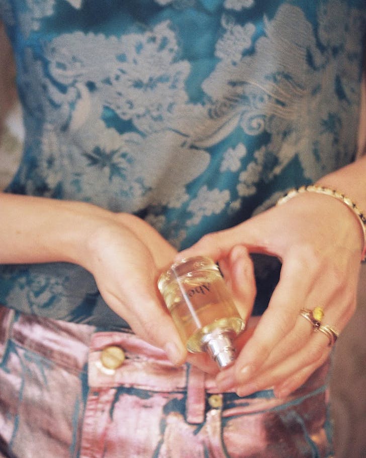 Someone in a floral shirt holds a bottle of Abel fragrance. 