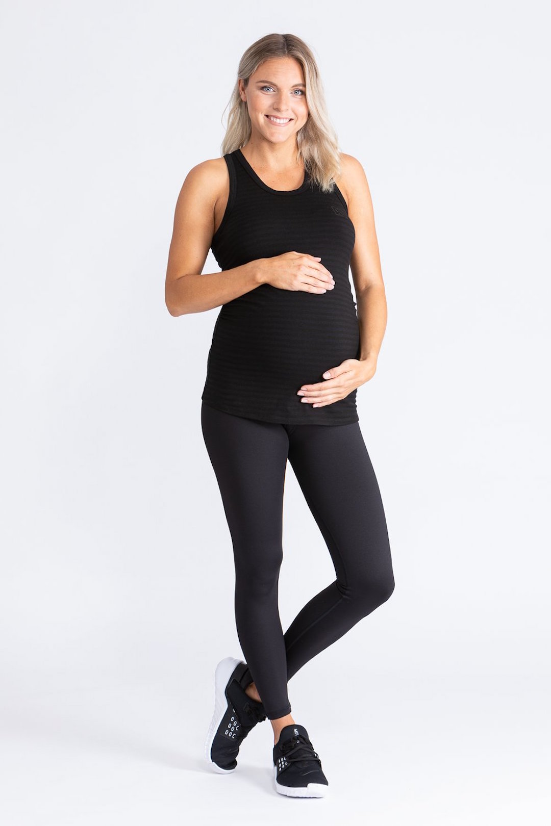 A pregnant woman wears a black singlet top and black tights.