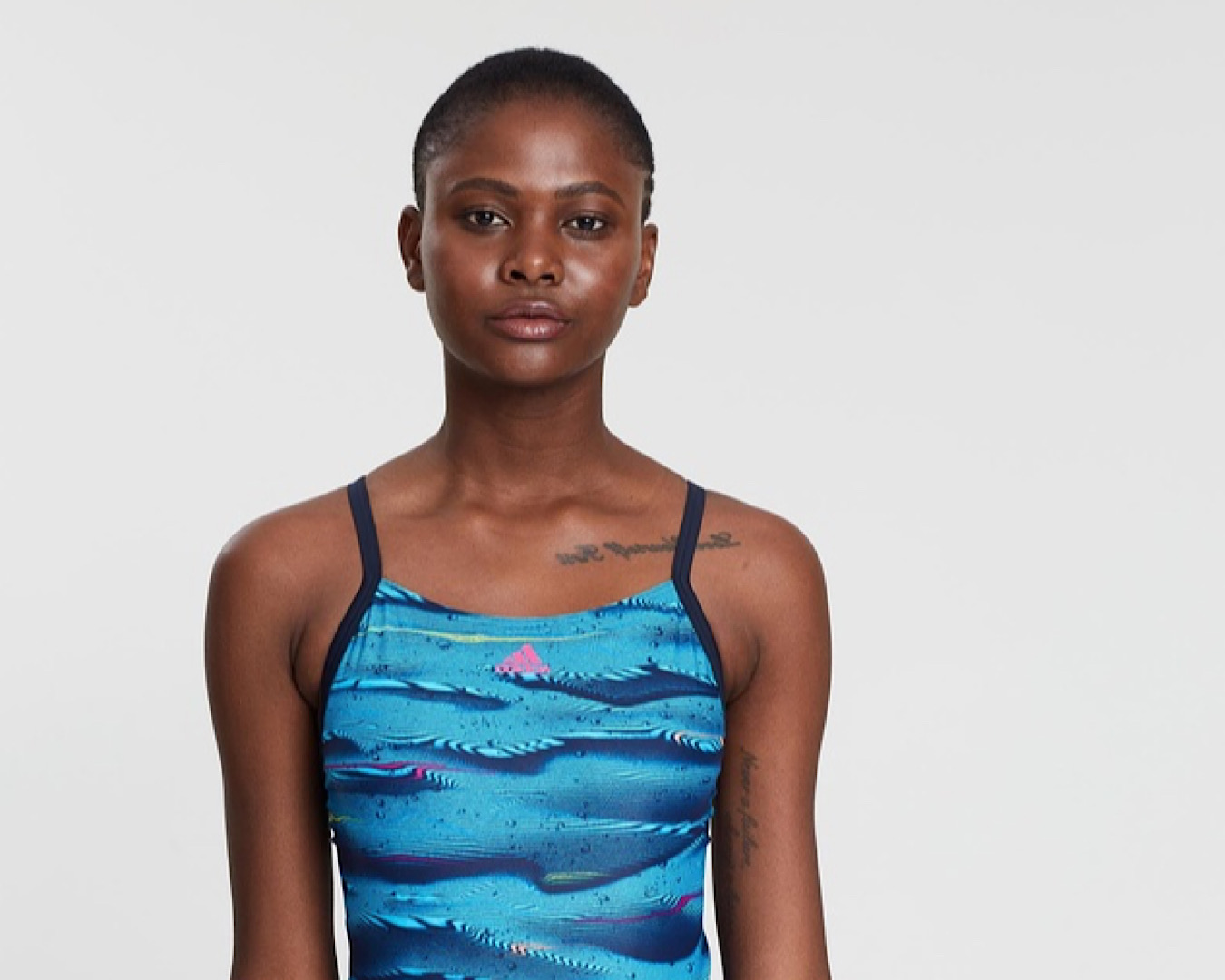 A woman looks confident in a dark blue one piece by Adidas, one of the coolest swimwear labels that’s actually practical.