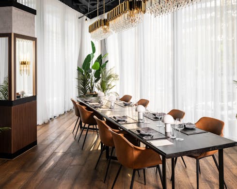 An indoor private dining table next to a floor-to-ceiling curtained window. The space is well-lit and intimate, while being minimal and classy.