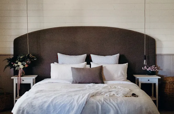 A queen bed sits in the middle of a bedroom with a timber bed head.