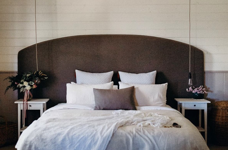 A queen bed sits in the middle of a bedroom with a timber bed head.