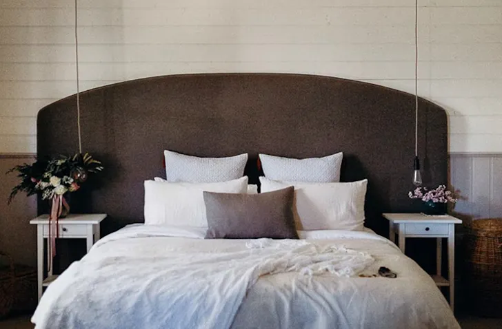 A queen bed sits in the middle of a bedroom with a timber bed head at a romantic getaways victoria stay.