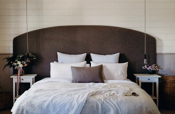 A queen bed sits in the middle of a bedroom with a timber bed head at a romantic getaways victoria stay.